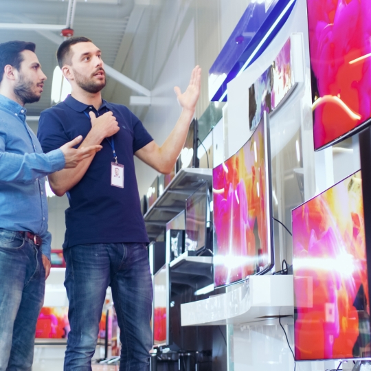 Ein Kunde mit einem Berater beim Fernseherkauf.