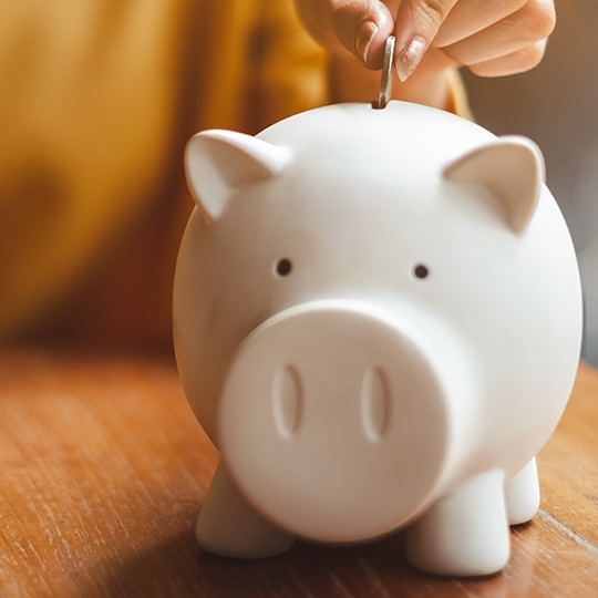 Eine Person legt Geld in ihr Sparschwein.