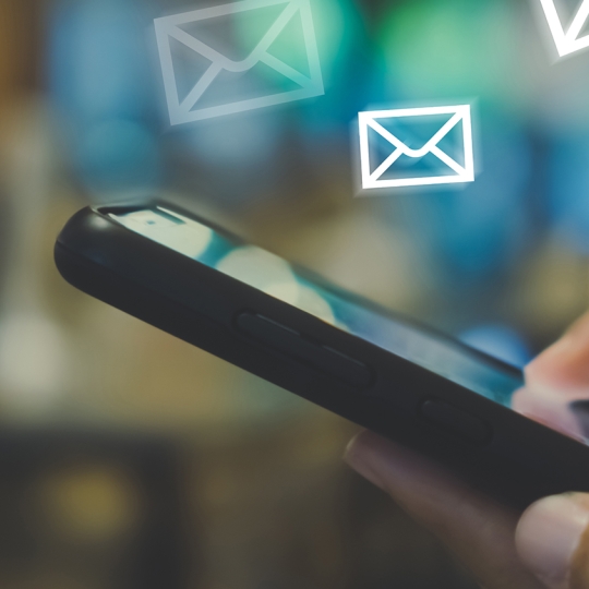 Smartphone in der Hand mit ganz vielen Mail-Icons