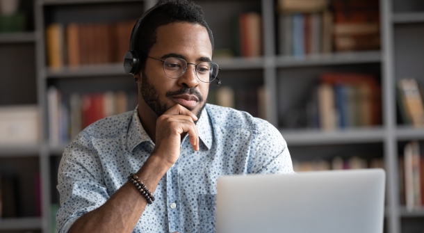 Eine Person hört sich etwas am Laptop an.