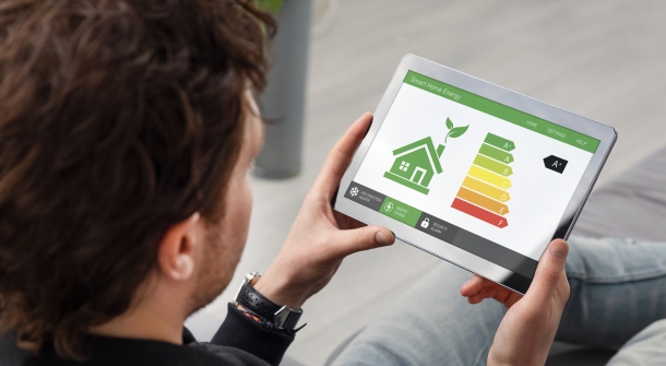 Jemand sieht sich auf einem Tablet die Energiesparstufe eines Smart Homes an.